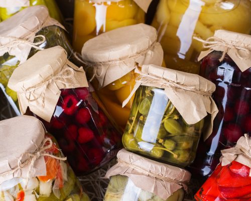 preserved-fermented-local-food-assortment-homemade-jars-with-variety-pickled-marinated-vegetables-fruit-compote-wooden-table-housekeeping-home-economics-harvest-preservation